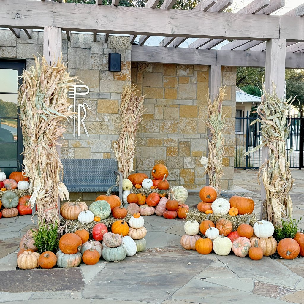 Outdoor Fall display featuring pumpkins and corstalks.