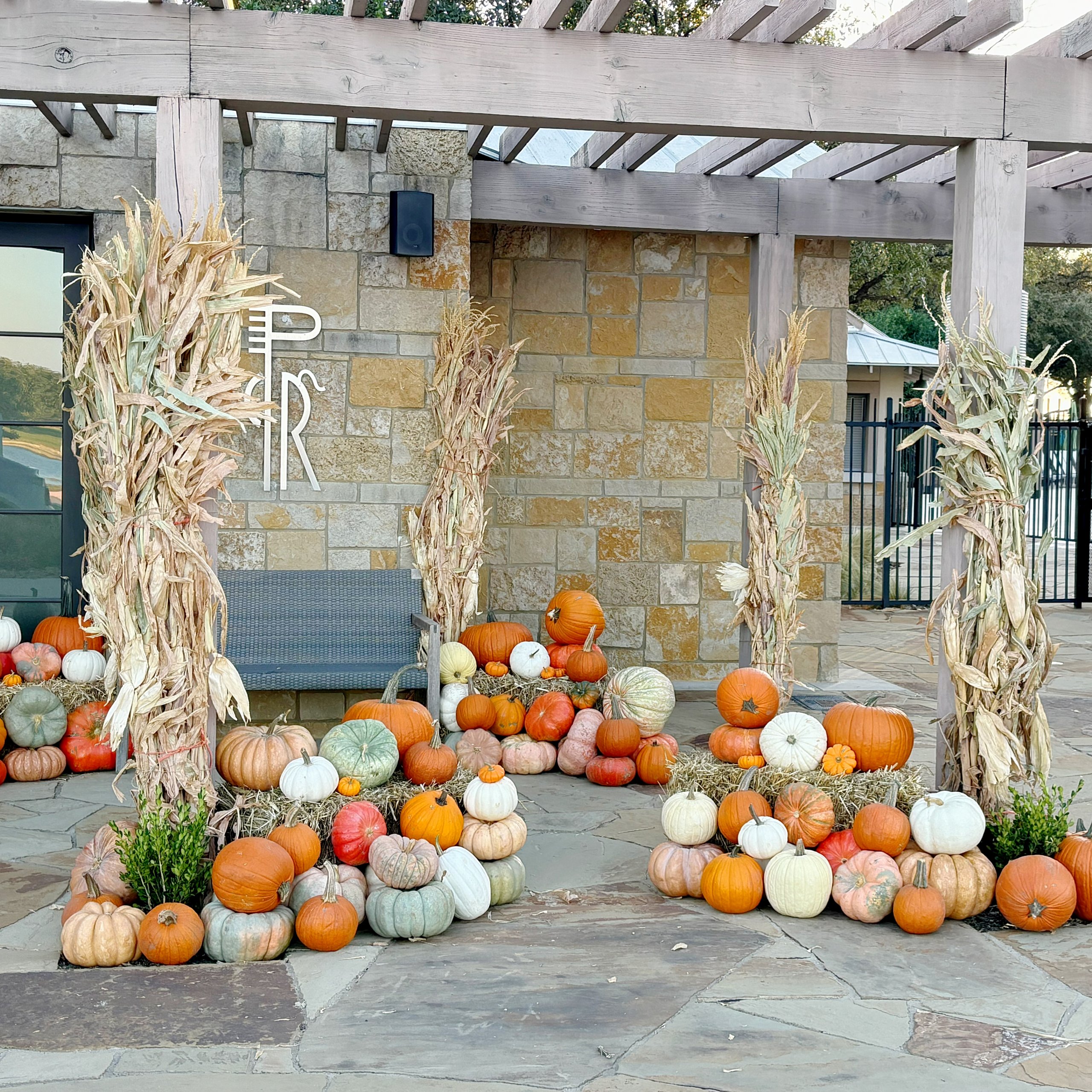Outdoor Fall display featuring pumpkins and corstalks.