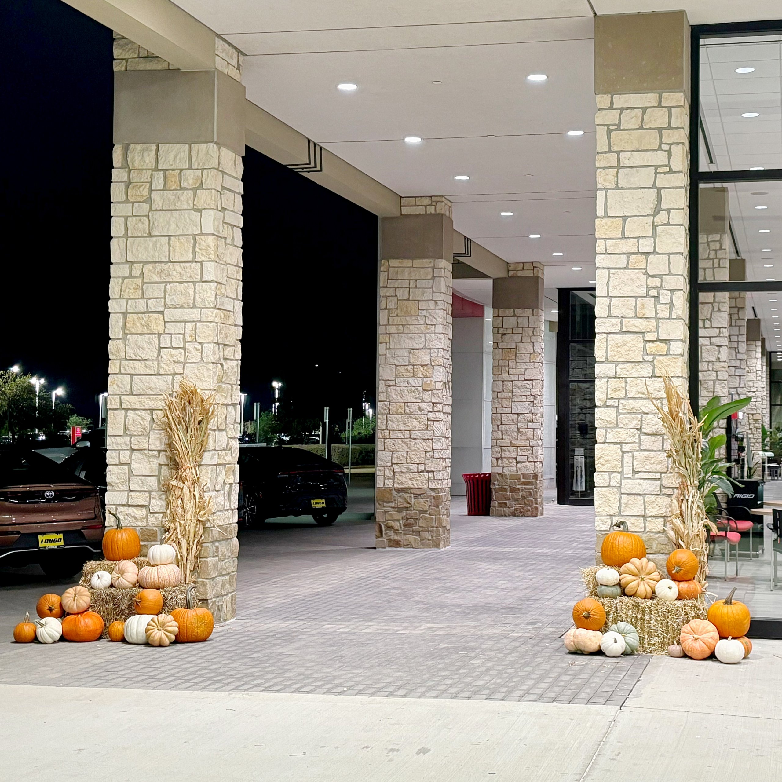 pumpkin display with pumpkins, hay, and cornstalks for car dealeriship.