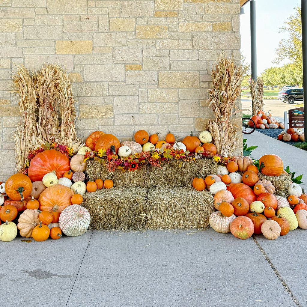 Elegant front porch with stacked pumpkin display and hay bales