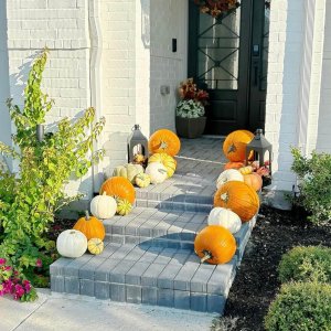 Simple front porch pumpkin display with stacked orange pumpkins on steps