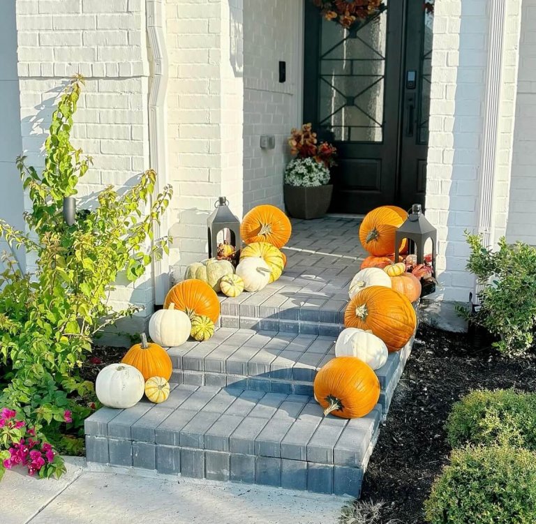 Simple front porch pumpkin display with stacked orange pumpkins on steps