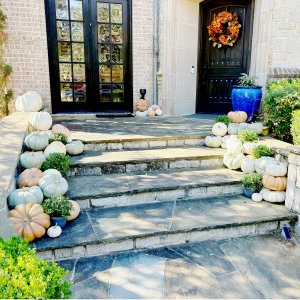 Front steps decorated with orange and white pumpkins for fall or white and pastel pumpkins.